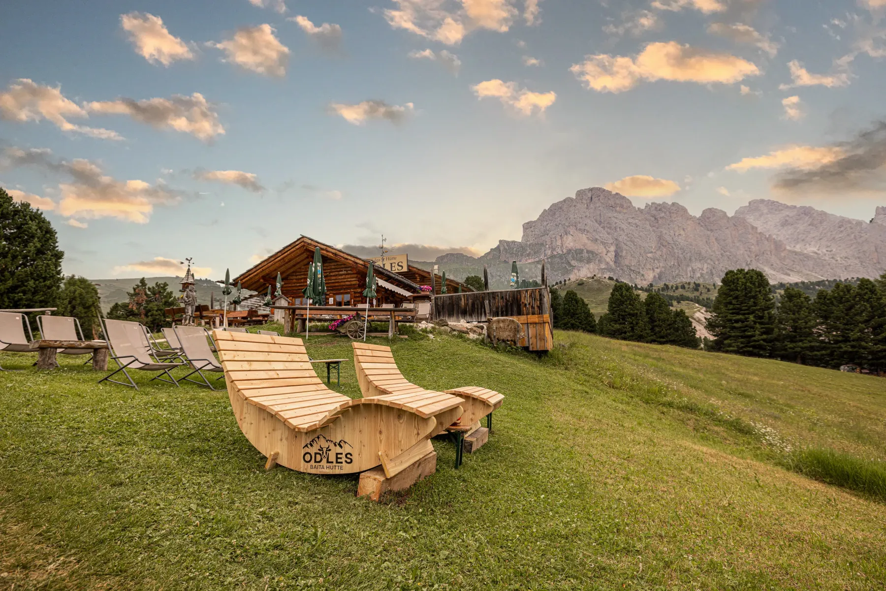 Sdraio in legno davanti alla Baita Odles con panorama dolomitico