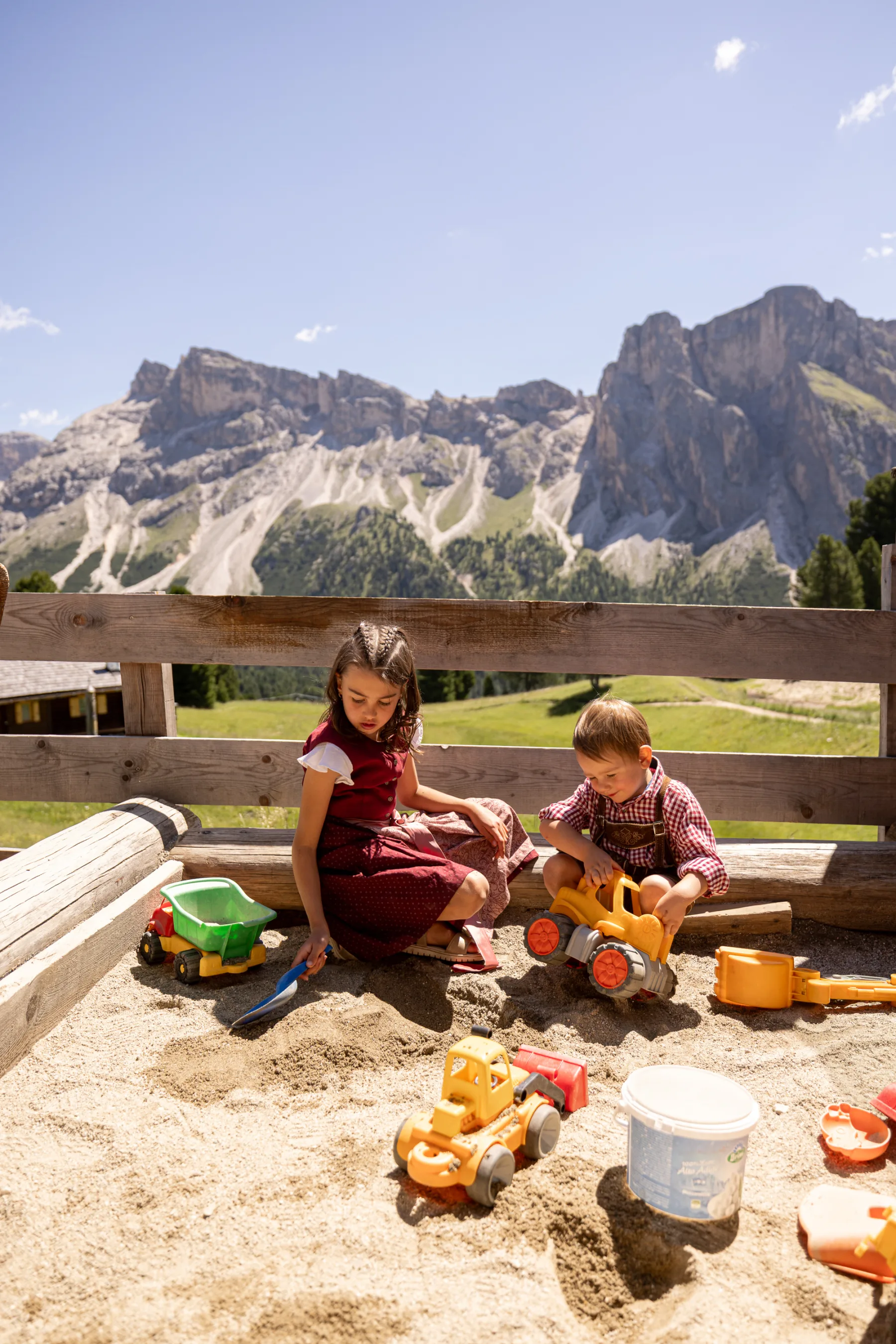 Kinder spielen im Sandkasten vor den Dolomiten
