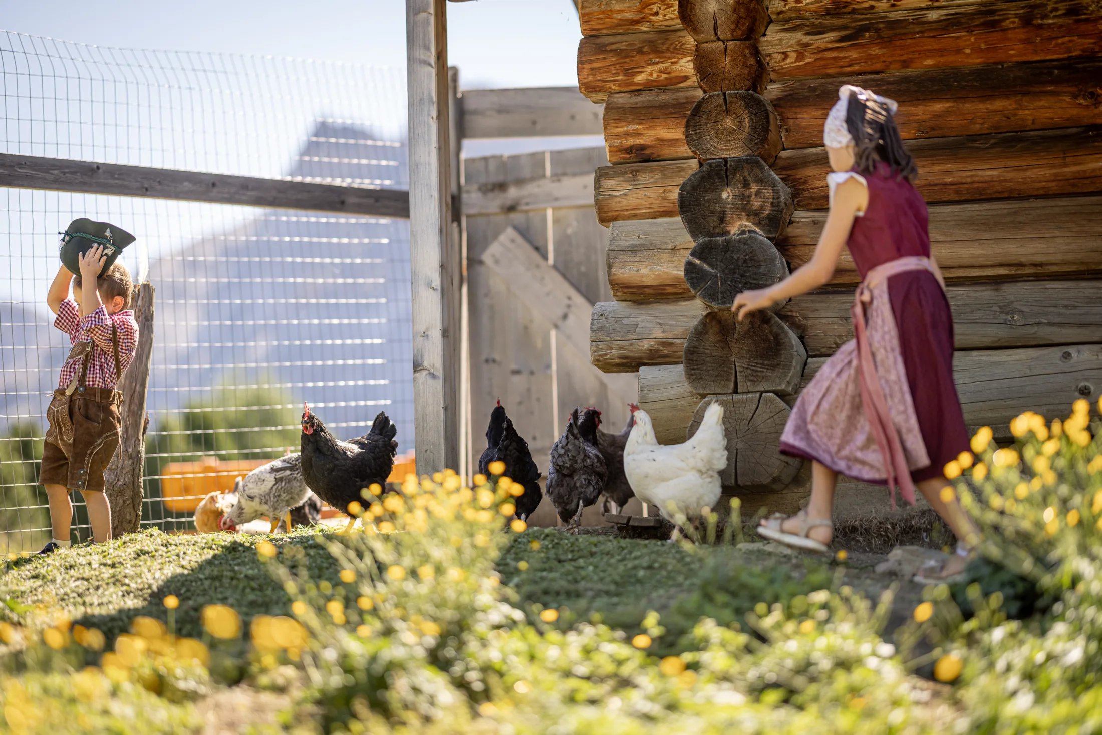 Bambini in costume tradizionale con le galline accanto alla stalla della Baita Odles