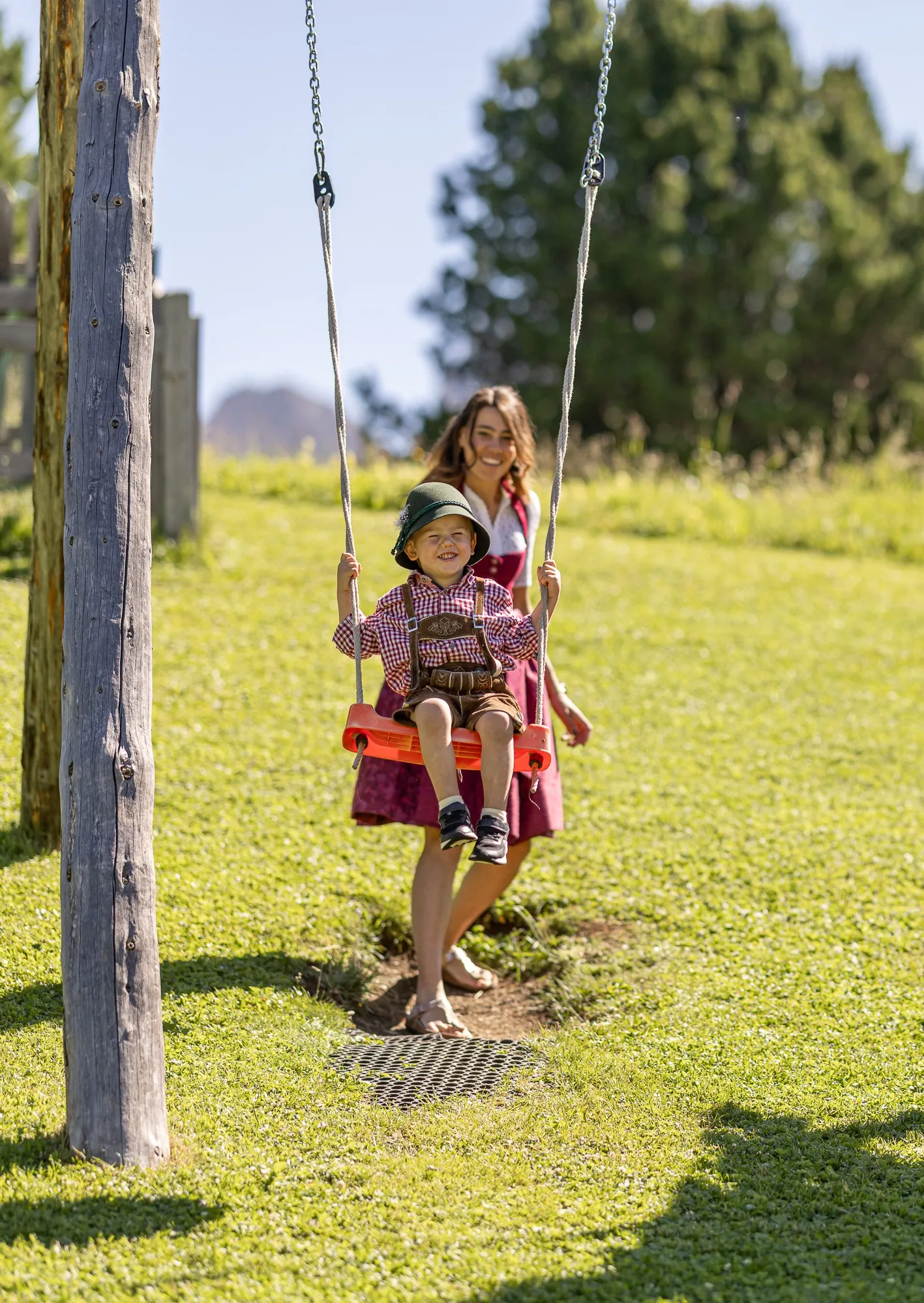 Una mamma spinge il bambino sull'altalena al parco giochi della Baita Odles