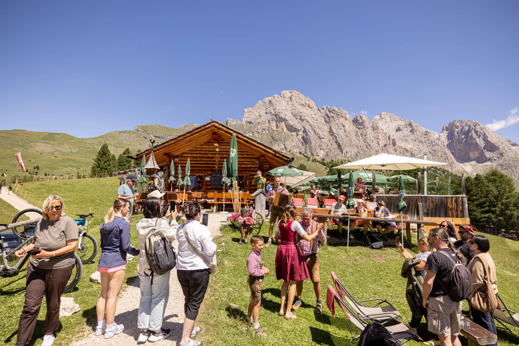 Tanzendes Paar in Tracht vor der Baita Odles